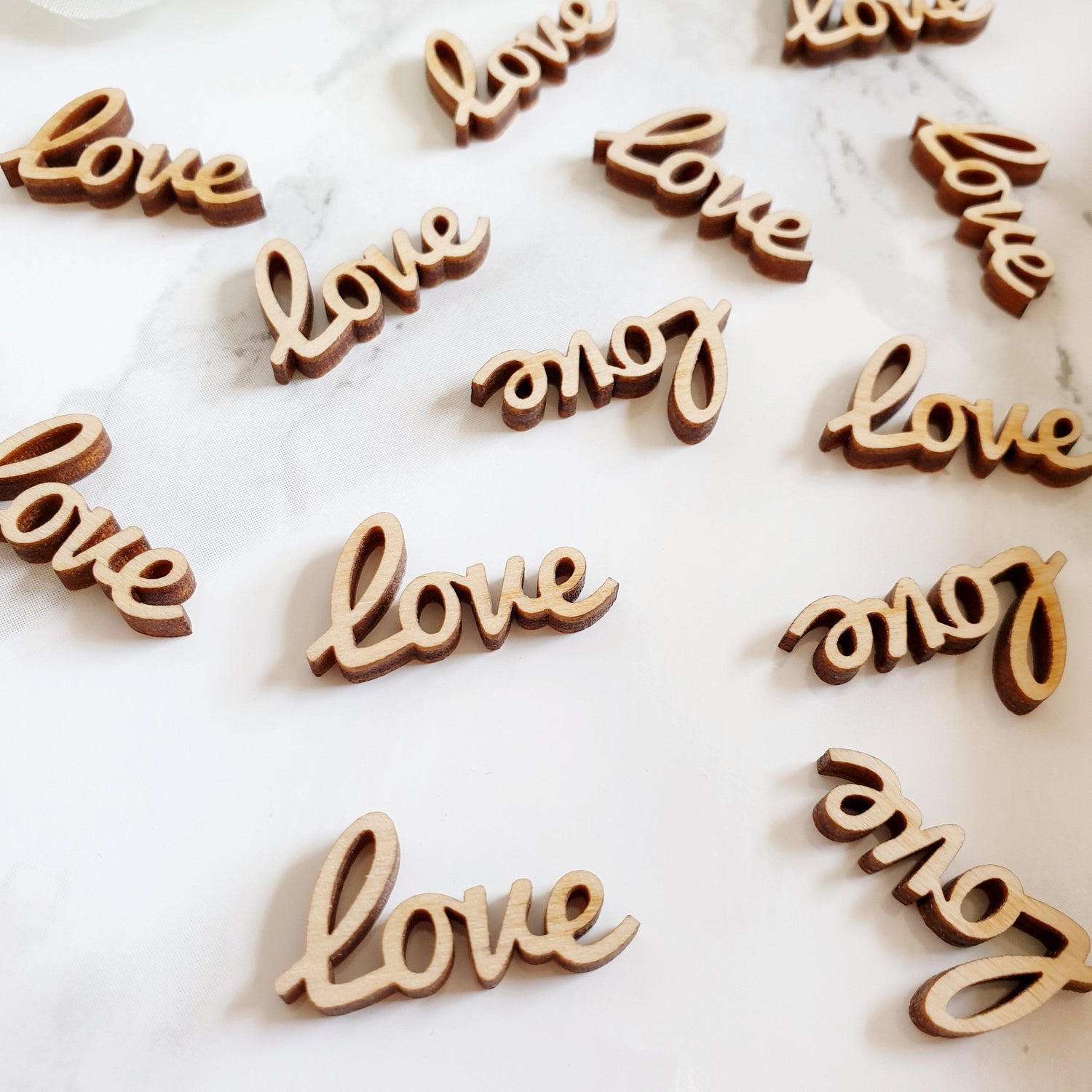 Laser cut love words made from wood sprinkled over a table.